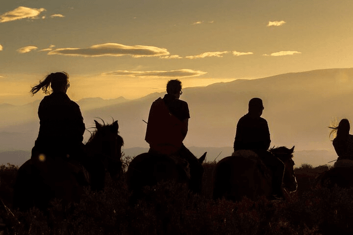 Silhouettes of riders against the sunset sky