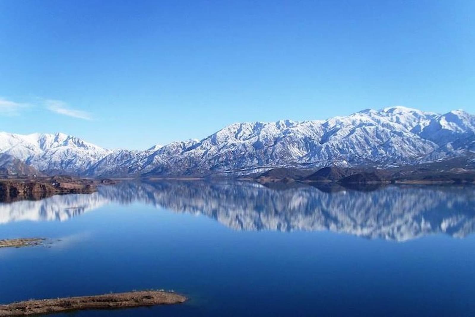 Mountains reflected in the still water of the Potrerillos reservoir