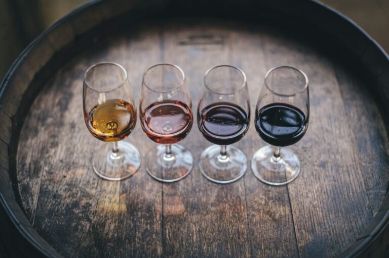 Copas de vino tinto y blanco servidas sobre una barrica