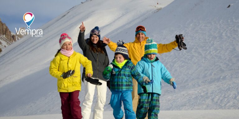 Familia sentada en la nieve con la cordillera de fondo